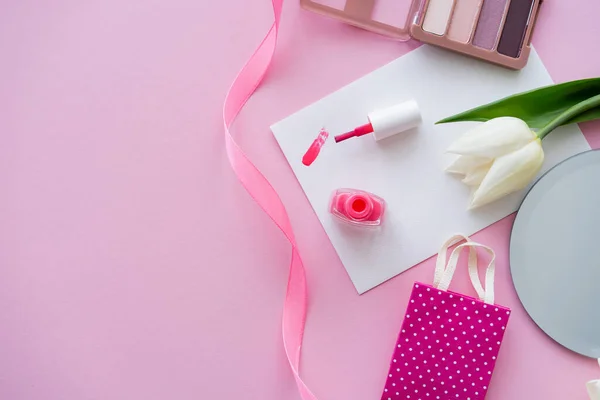 Ansicht von oben Pinselstrich von Nagellack auf Karte in der Nähe von Tulpe und Lidschatten-Palette auf rosa — Stockfoto