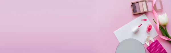 Вид зверху на пензлик на листівці біля лаку для нігтів, білий тюльпан, тінь очей і сумка для покупок на рожевому, банер — стокове фото