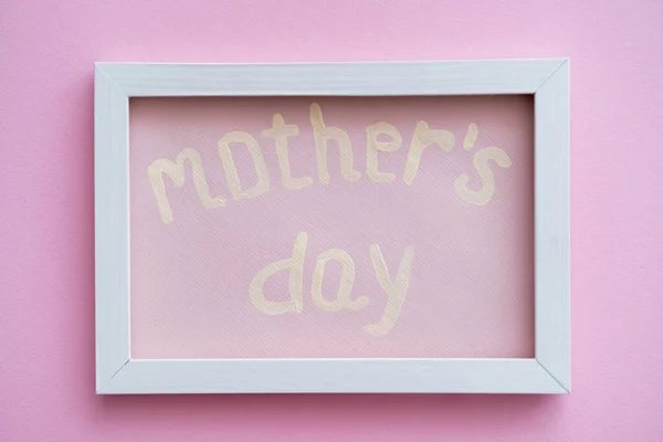 Top view of greeting card with mothers day lettering in white frame on pink — Stock Photo