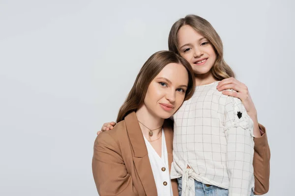 Madre e hija en ropa casual elegante abrazo aislado en gris - foto de stock