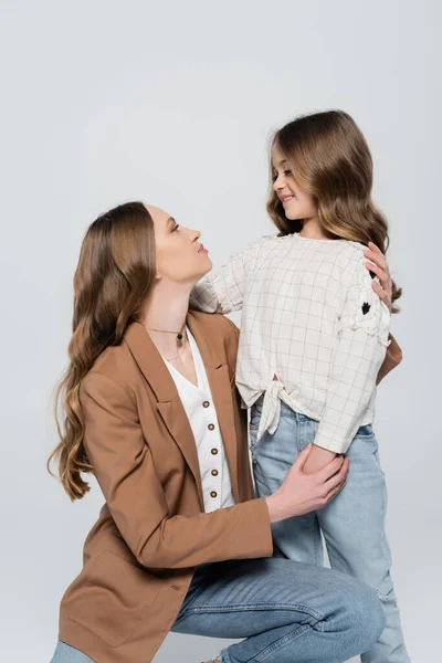 Mother and daughter with long hair embracing and looking at each other isolated on grey — Stock Photo