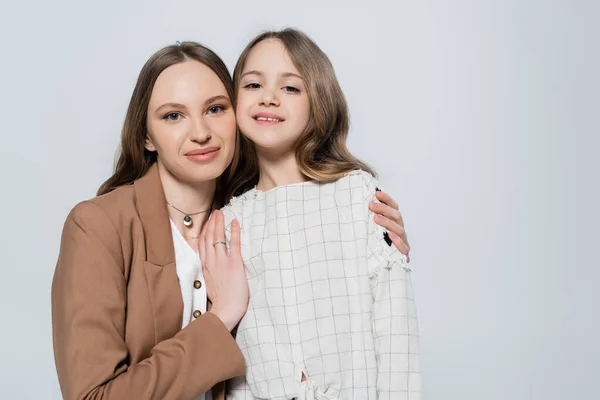 Frau umarmt glückliches Kind und blickt in Kamera isoliert auf grau — Stockfoto