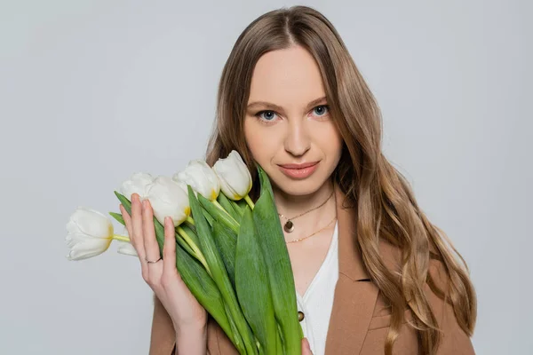 Mulher bonita com tulipas brancas olhando para a câmera isolada no cinza — Fotografia de Stock