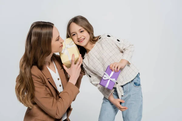 Woman and smiling girl holding gift boxes isolated on grey — Stock Photo