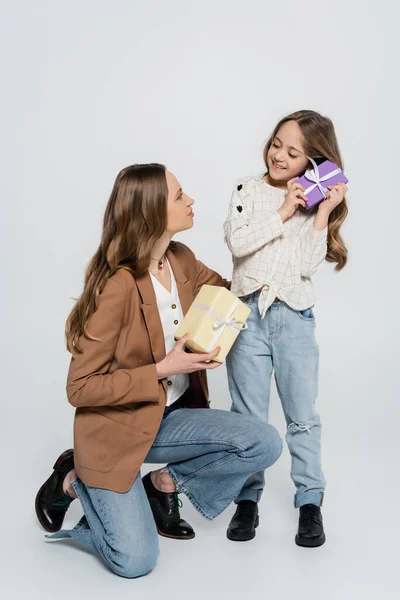 Vista completa de la mujer y el niño sosteniendo cajas de regalo sobre fondo gris - foto de stock