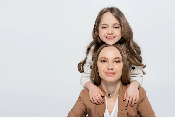 Alegre niño abrazando hombros de feliz mamá mientras mira a la cámara aislada en gris - foto de stock