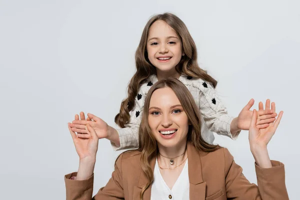 Eccitati madre e figlia guardando la fotocamera mentre si tiene le mani isolate sul grigio — Foto stock