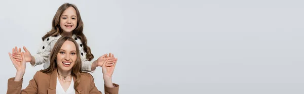 Mujer cogida de la mano de hija alegre aislada en gris, bandera — Stock Photo