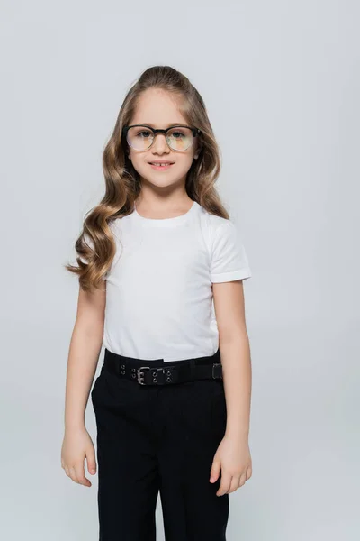 Vue de face de la fille en t-shirt blanc et lunettes regardant la caméra isolée sur gris — Stock Photo