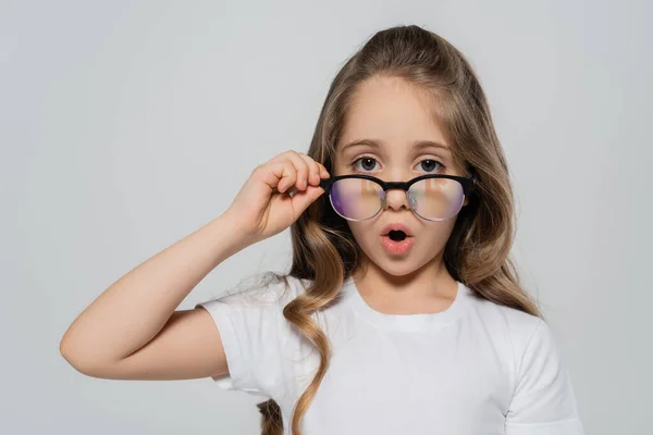 Fille étonnée regardant caméra sur lunettes isolées sur gris — Photo de stock