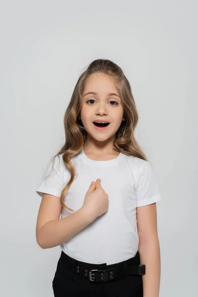 Fille étonnée en t-shirt blanc pointant du doigt elle-même isolé sur gris — Photo de stock