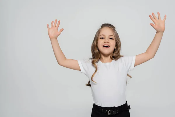 Aufgeregtes Mädchen im weißen T-Shirt winkt mit den Händen, während sie vereinzelt in die Kamera schaut — Stockfoto