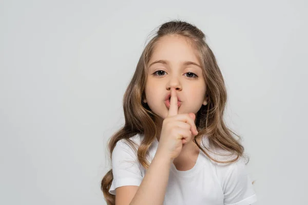 Chica con el pelo largo mostrando signo de silencio mientras mira a la cámara aislada en gris - foto de stock