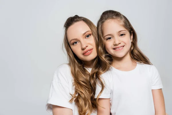 Mother and daughter with long hair looking at camera isolated on grey — Stock Photo