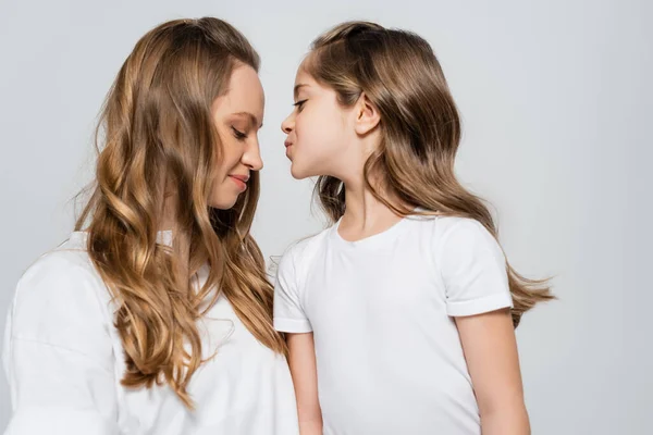 Girl in white t-shirt kissing happy mother isolated on grey — Stock Photo