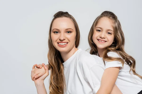 Mulher e menina feliz olhando para a câmera enquanto segurando as mãos isoladas no cinza — Fotografia de Stock