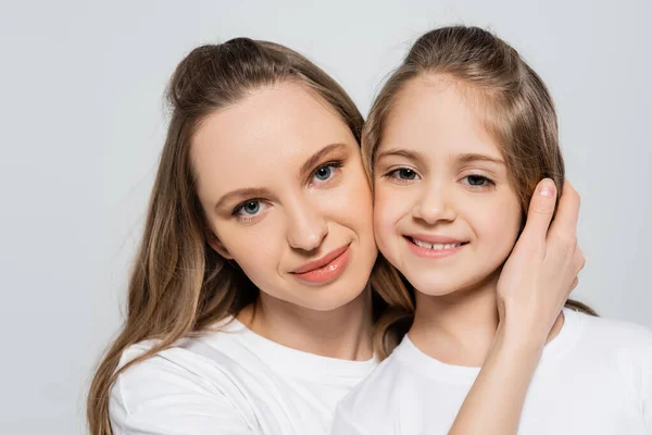 Woman hugging happy daughter and looking at camera isolated on grey — Stock Photo