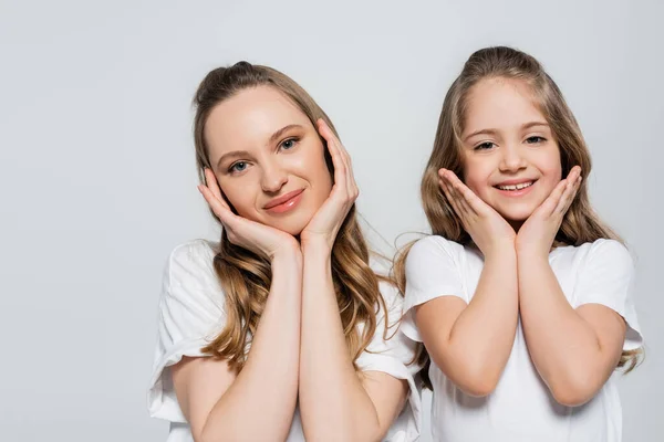 Zufriedene Mutter und Kind mit Händen in der Nähe Gesicht blickt in Kamera isoliert auf grau — Stockfoto