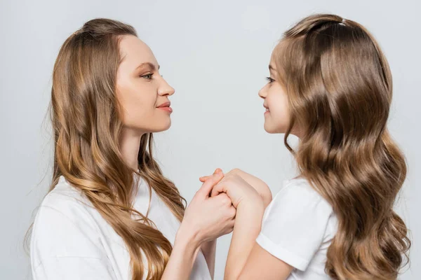 Side view of girl and woman looking at each other and holding hands isolated on grey — Stock Photo