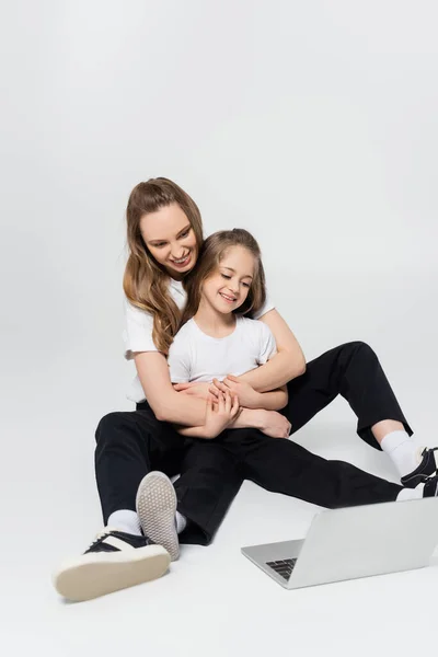 Glückliche Mutter und Tochter umarmen und Film auf grau — Stockfoto
