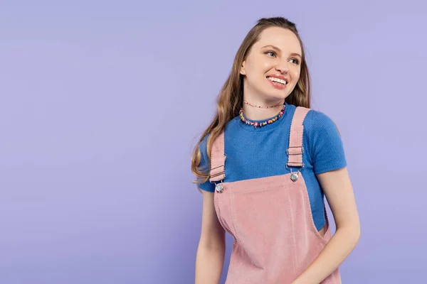 Portrait of joyful woman in overall dress smiling isolated on purple — Stock Photo