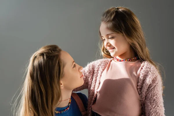 Cheerful mother and daughter looking at each other isolated on grey — Stock Photo