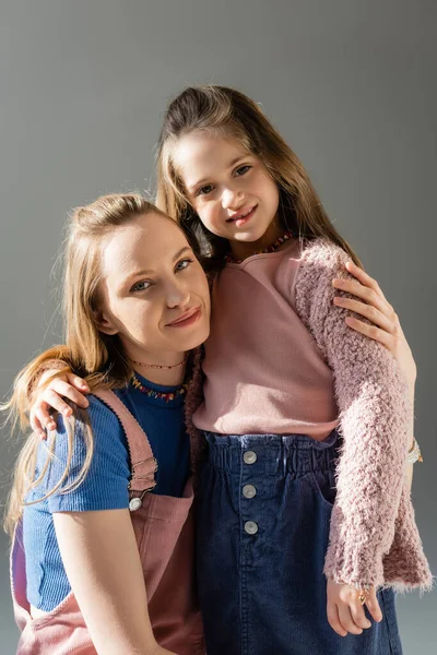 Cheerful mother and daughter hugging isolated on grey — Stock Photo