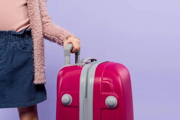 Cropped view of kid holding luggage handle isolated on purple — Stock Photo