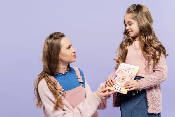 Madre felice guardando figlia allegra con biglietti di auguri isolati su viola, concetto di giorno di madri — Foto stock