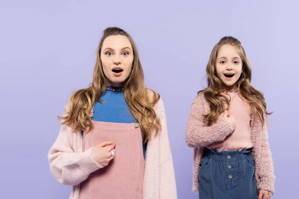 Здивована мати і дочка вказують на себе ізольовані на фіолетовому — стокове фото
