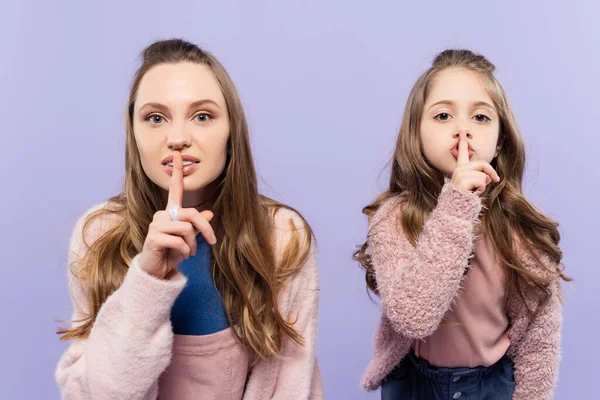 Mãe e filha mostrando sinal de silêncio isolado em roxo — Fotografia de Stock