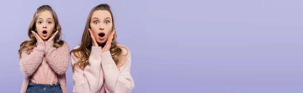 Shocked mother and daughter looking at camera isolated on purple, banner — Stock Photo