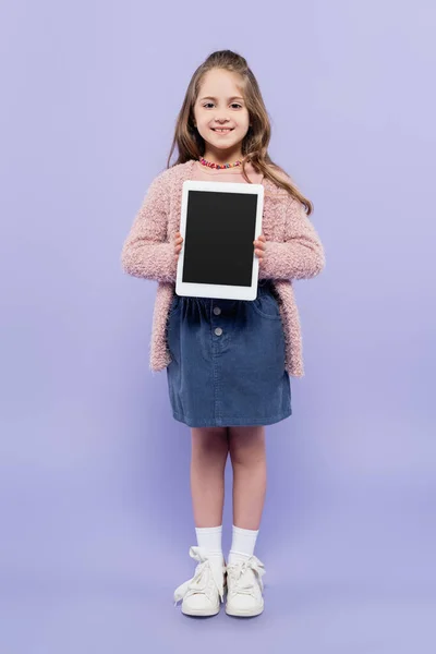 Volle Länge des fröhlichen Mädchens hält digitale Tablette mit leerem Bildschirm auf lila — Stockfoto