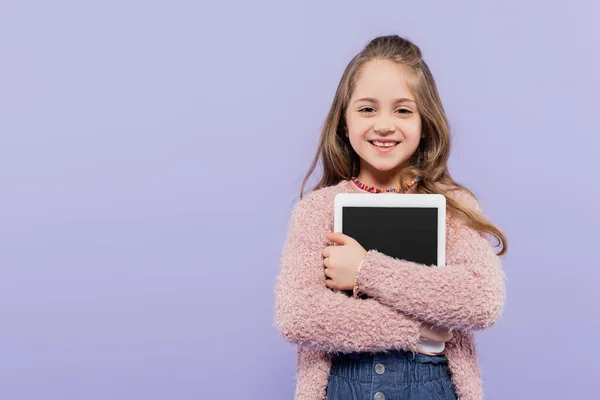 Chica alegre abrazando tableta digital con pantalla en blanco aislado en púrpura - foto de stock