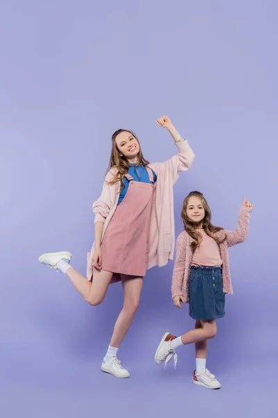 Longitud completa de feliz niño y madre divirtiéndose juntos en púrpura - foto de stock