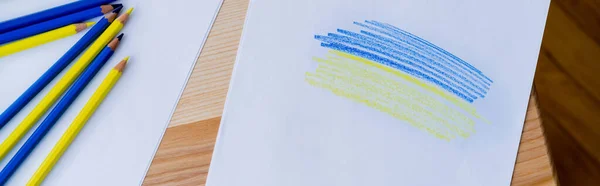 Vue du dessus des crayons de couleur près du papier blanc avec traits bleus et jaunes, bannière — Photo de stock