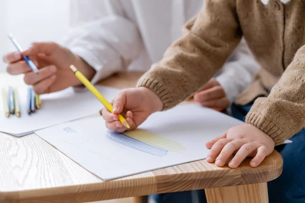 Cropped view of patriotic child drawing ukrainian flag near blurred mother — Stock Photo