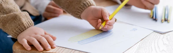 Vue partielle de la fille patriotique dessin drapeau bleu et jaune près de maman floue, bannière — Photo de stock