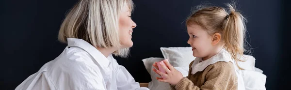Side view of smiling woman giving gift box to little daughter in bedroom, banner — Stock Photo