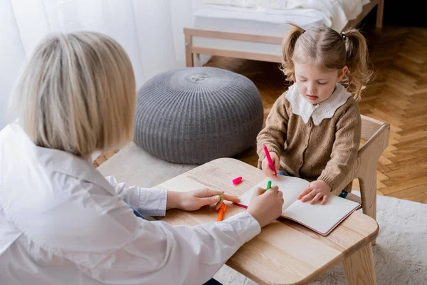 Высокий угол зрения матери и дочери рисунок с красочными ручками войлока в ноутбуке — стоковое фото