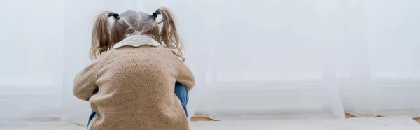 Back view of depressed girl with ponytails sitting on floor at home, banner — Stock Photo