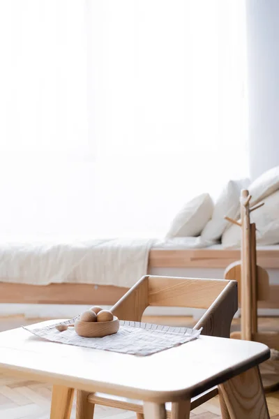 Wooden bowl with balls on table in nursery near bed on blurred background — Stock Photo