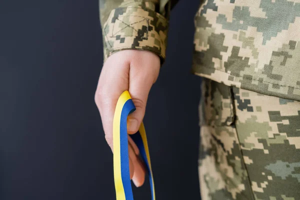 Vue partielle de la femme militaire tenant un ruban bleu et jaune isolé sur noir — Photo de stock