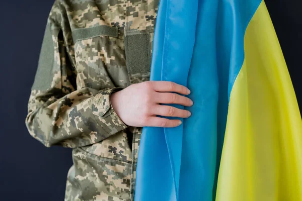 Vista recortada de mujer militar con bandera ucraniana aislada en negro - foto de stock