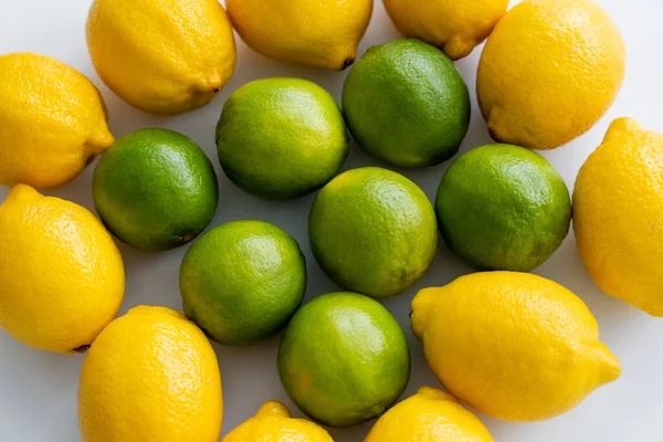 Draufsicht auf frische Limetten und Zitronen auf weißem Hintergrund — Stockfoto