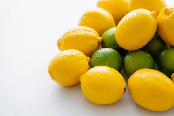 Vista en ángulo alto de limones orgánicos sobre limas sobre fondo blanco - foto de stock