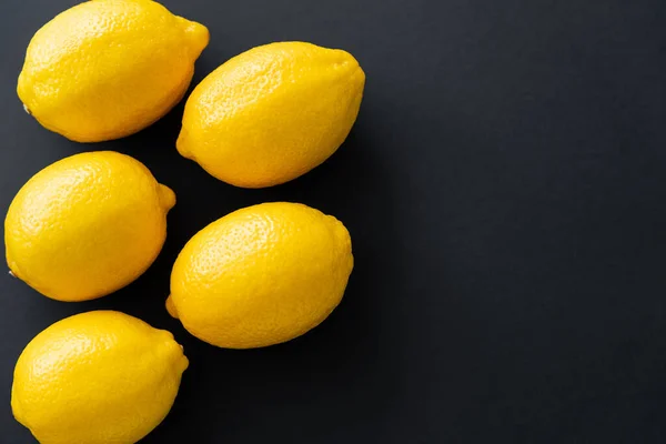 Flache Lage von saftigen gelben Zitronen auf schwarzem Hintergrund — Stockfoto