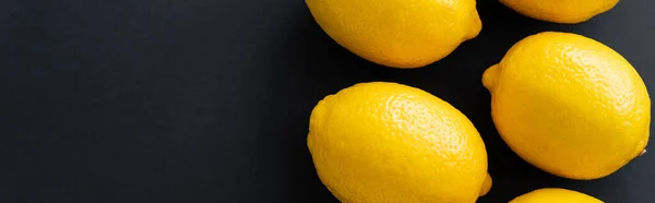 Top view of bright lemons on black background, banner — Stock Photo