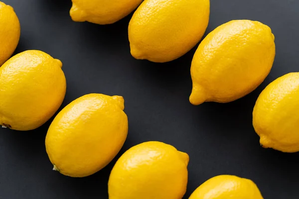 Top view of fresh lemons in rows on black background — Stock Photo