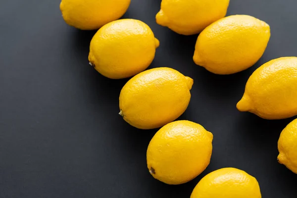 Flat lay of juicy and bright lemons on black background — Stock Photo